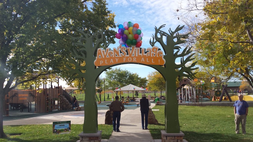 Aven's Village sign, playground with adults and children